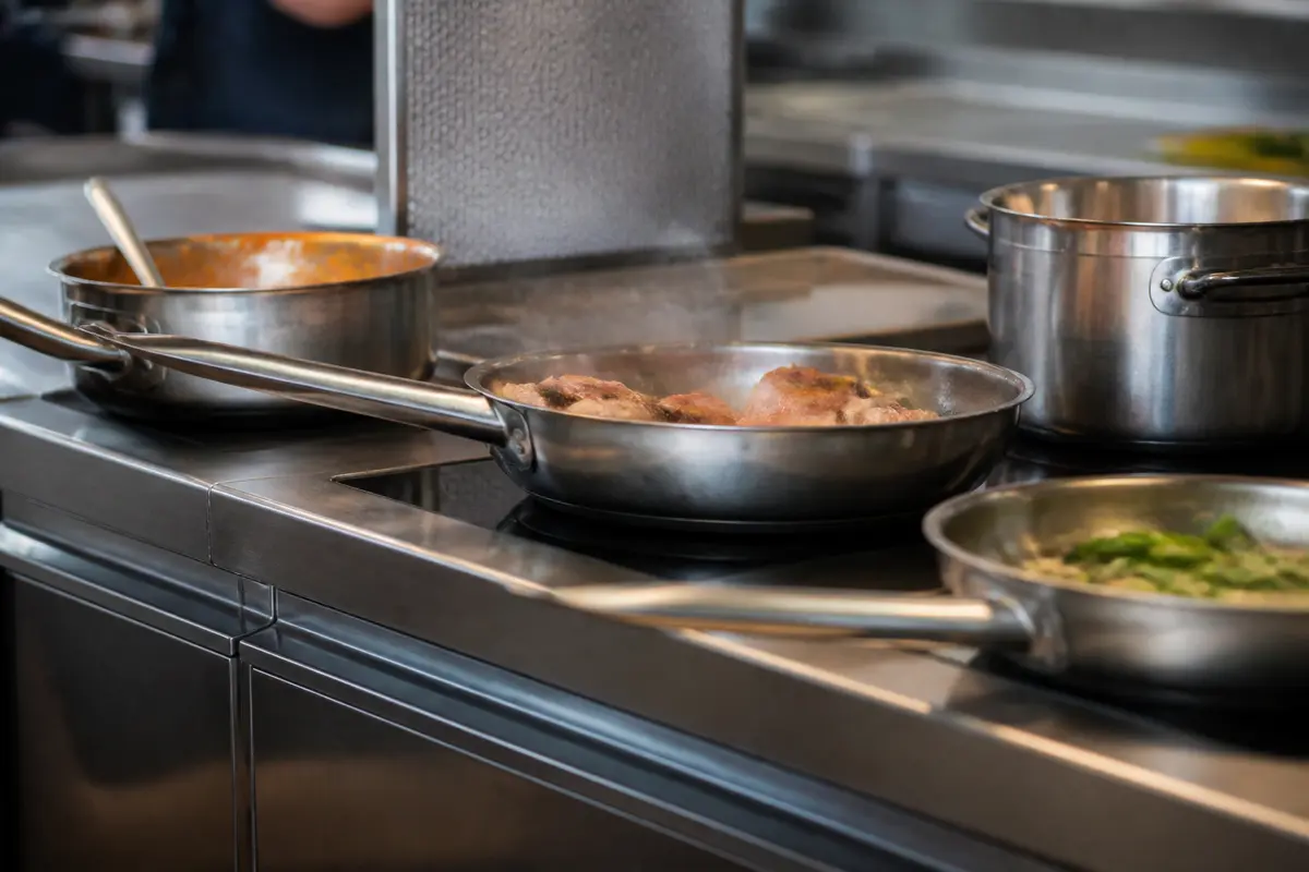 Poêles en inox sur poêle à induction professionnelle dans une cuisine moderne